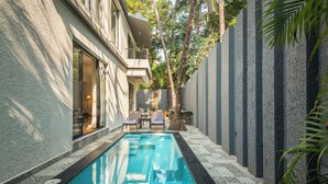 A swimming pool with a tiled deck, a lounge area with chairs, and a building with a balcony. - TBK Villa Calangute (Calangute)
