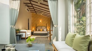 A bedroom with a bed, bedside table, lamp, and a view of greenery outside. - TBK Villa Calangute (Calangute)
