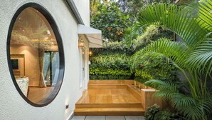 A modern building with a circular window, a wooden staircase, and lush greenery. - TBK Villa Calangute (Calangute)