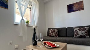 Ett modernt vardagsrum med en soffa, ett soffbord med en flaska och glas, och ett fat med skivor av vattenmelon.