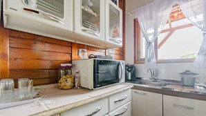 A compact kitchen with white cabinets, a microwave, and a sink. - Casa p 5 Pessoas Perto das Praias e Beto Carrero (Penha)