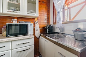 Une cuisine de taille réduite équipée d’un four à micro-ondes, d’un évier et de placards.