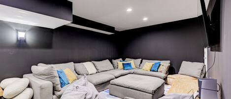 Una sala moderna con un sofá modular, un reposapiés y un televisor de pantalla plana.