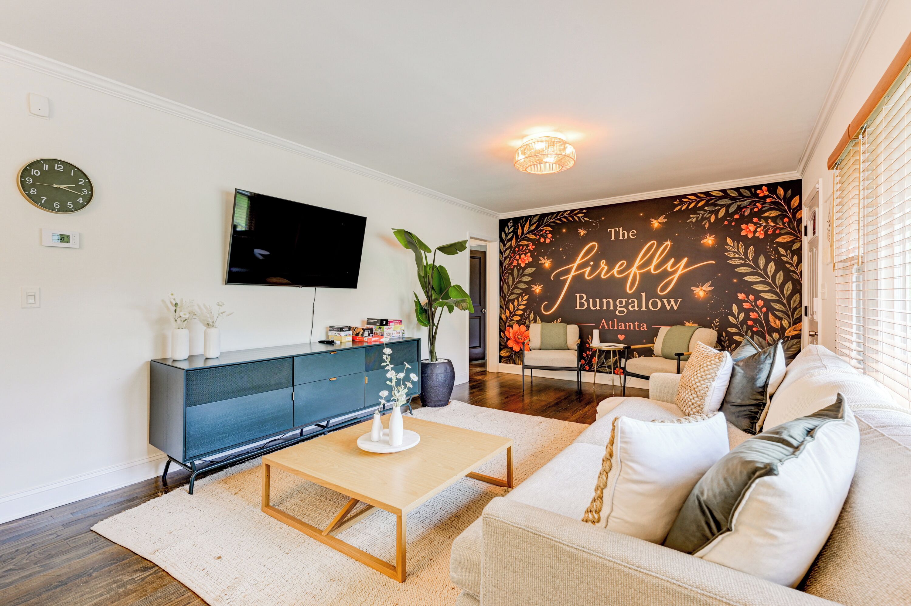 A modern living room with a flat-screen TV, a blue cabinet, a wooden coffee table, a beige sofa, and a wall mural.