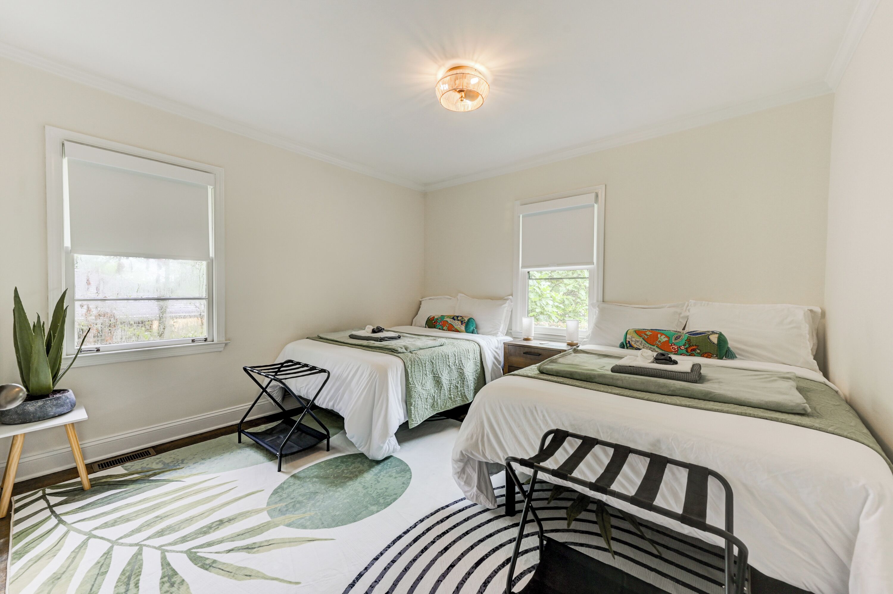 Quarto com duas camas, uma mesinha com uma planta e um radiador.