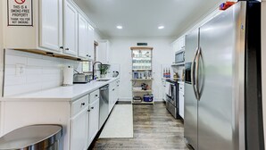 A smoke-free kitchen with white cabinets, stainless steel appliances, and a built-in microwave. - Boutique ATL Escape Movie Room and Covered Deck (Atlanta)