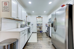 A smoke-free kitchen with white cabinets, stainless steel appliances, and a built-in microwave. - Boutique ATL Escape Movie Room and Covered Deck (Atlanta)