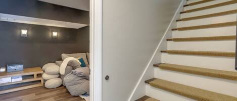 A staircase with a wooden handrail and carpeted steps, leading to a landing with a sofa and pillows.