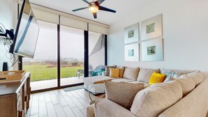 Ein modernes Wohnzimmer mit einer großen Couch, einem Flachbildfernseher und einem Deckenventilator.