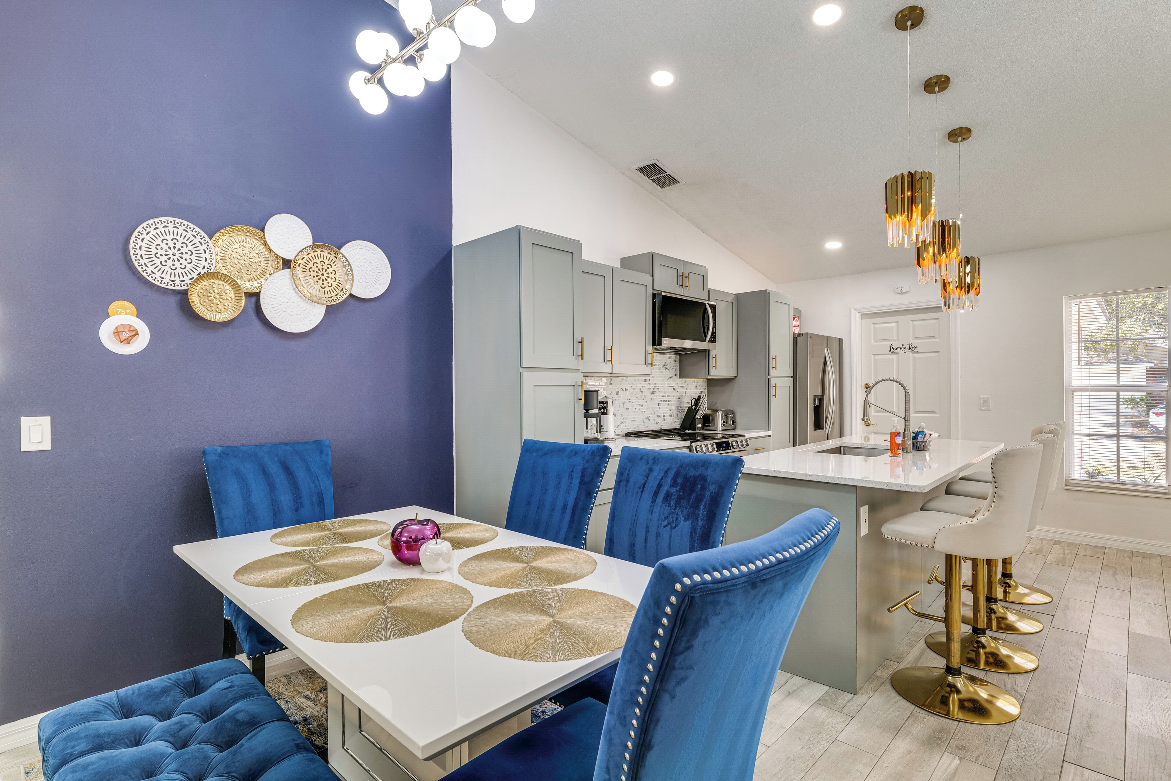 A modern kitchen with grey cabinets, a white countertop, and a stainless steel microwave.