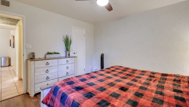 A bedroom with a bed, a dresser, a ceiling fan, and a door. - Walk to Waterfront! Couples Retreat in Old Town (Scottsdale)