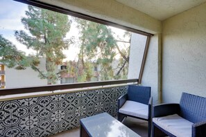 A balcony with patterned tiles, two wicker chairs, and a small table. - Pool & Hot Tub at Gem in the Heart of Old Town! (Scottsdale)