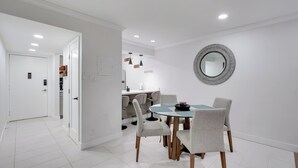 Een moderne eetruimte met een ronde tafel, vier stoelen en een spiegel aan de muur.