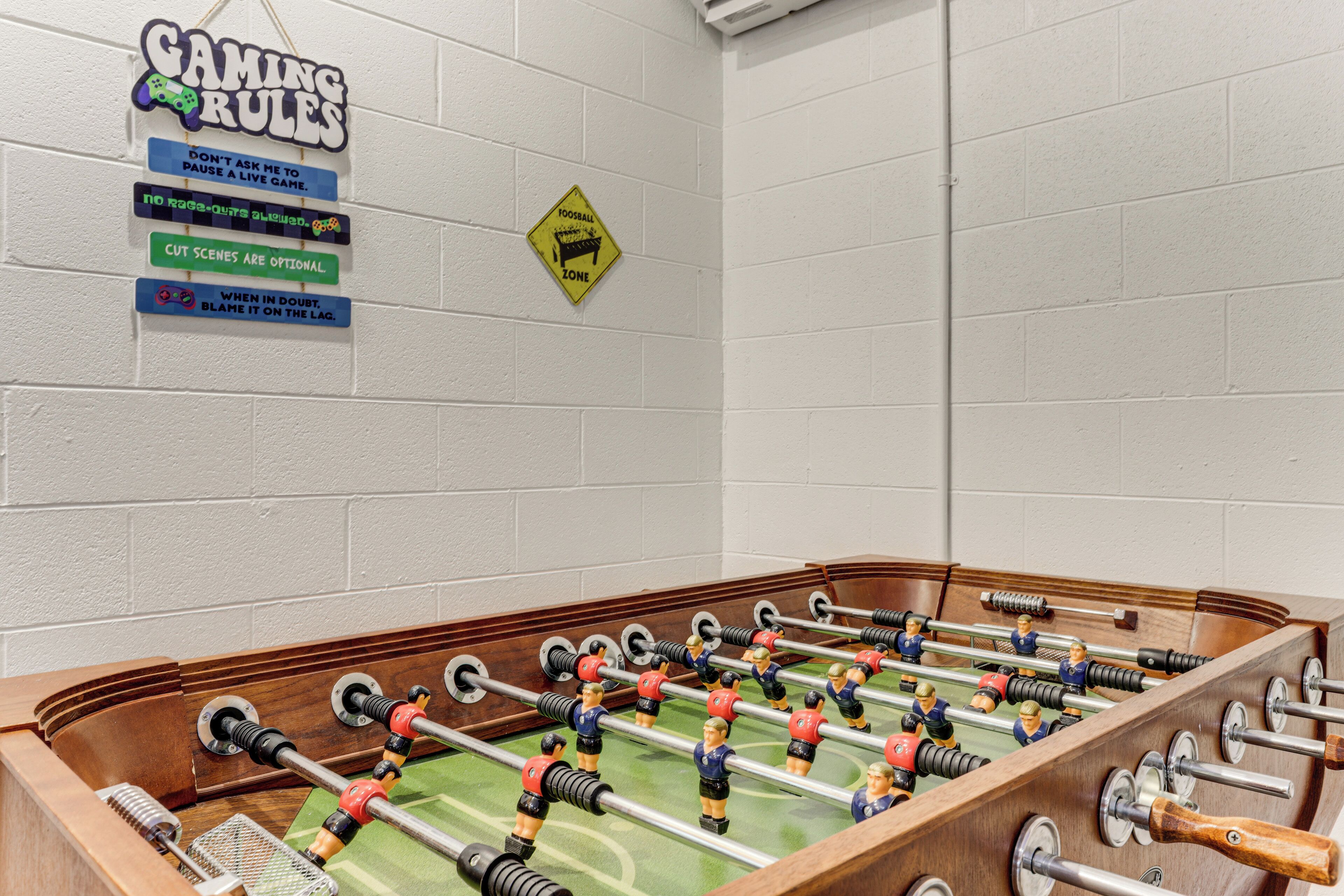 A foosball table with a sign listing gaming rules and a yellow sign indicating a football zone.