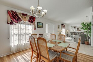 Un comedor con una mesa de madera, sillas y una araña.