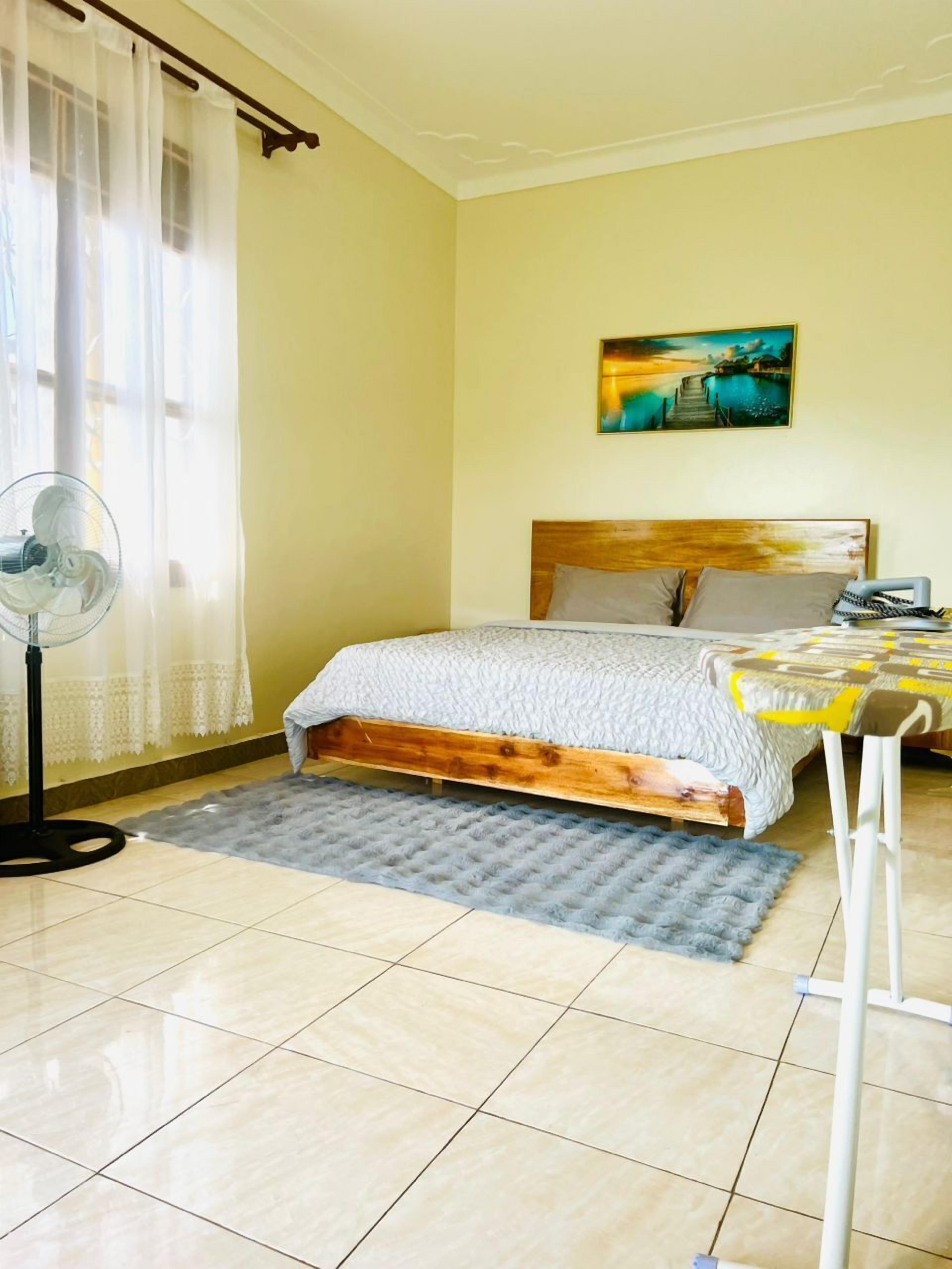 Une chambre à coucher avec un lit, un ventilateur, une table et un tableau accroché au mur.