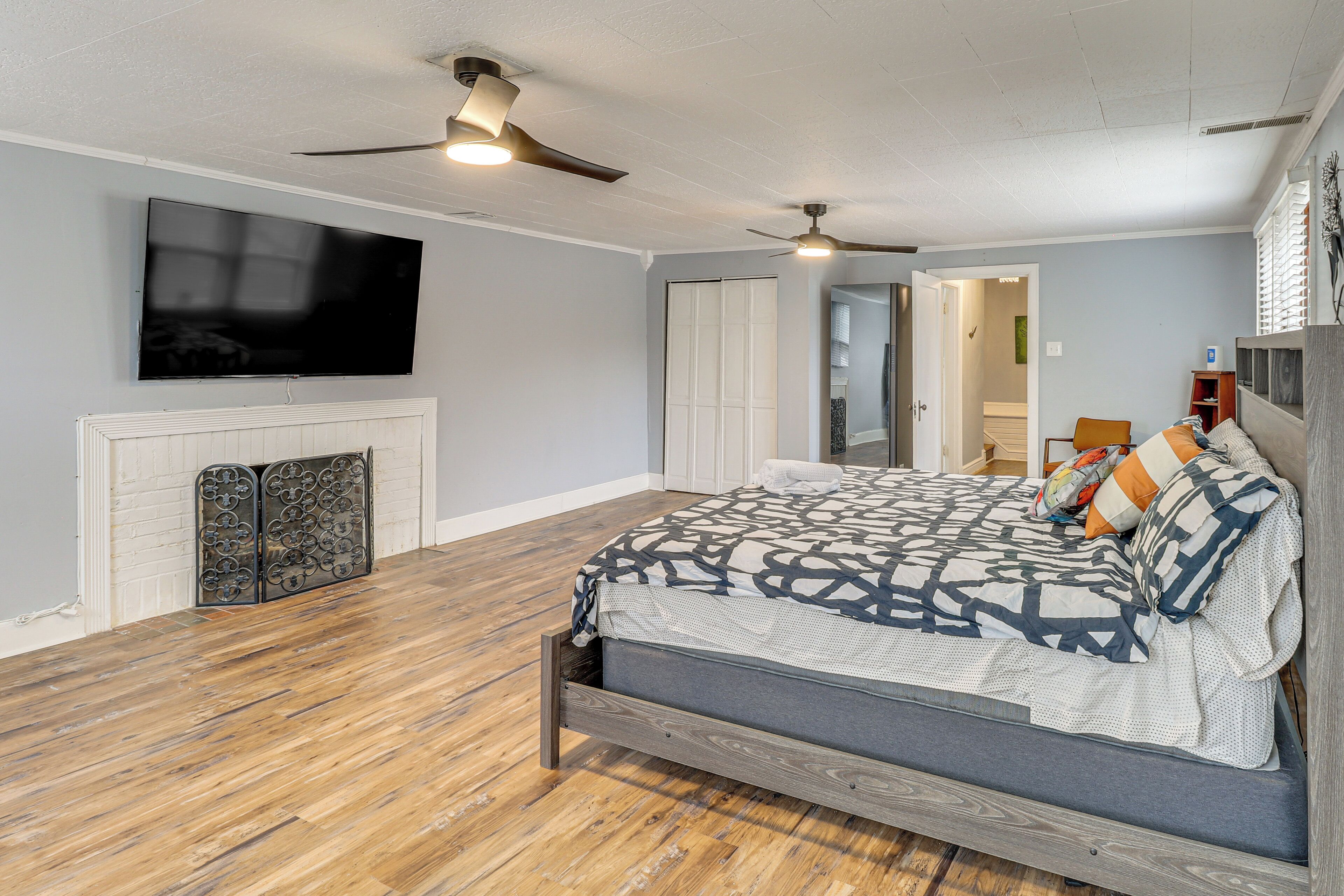 A bedroom with a bed, a TV mounted on the wall, and a ceiling fan.