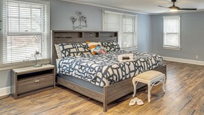 A bedroom with a wooden bed, a nightstand, a bench, and a ceiling fan. - Lakeside Clifton Heights Home Near Forest Park (St. Louis)