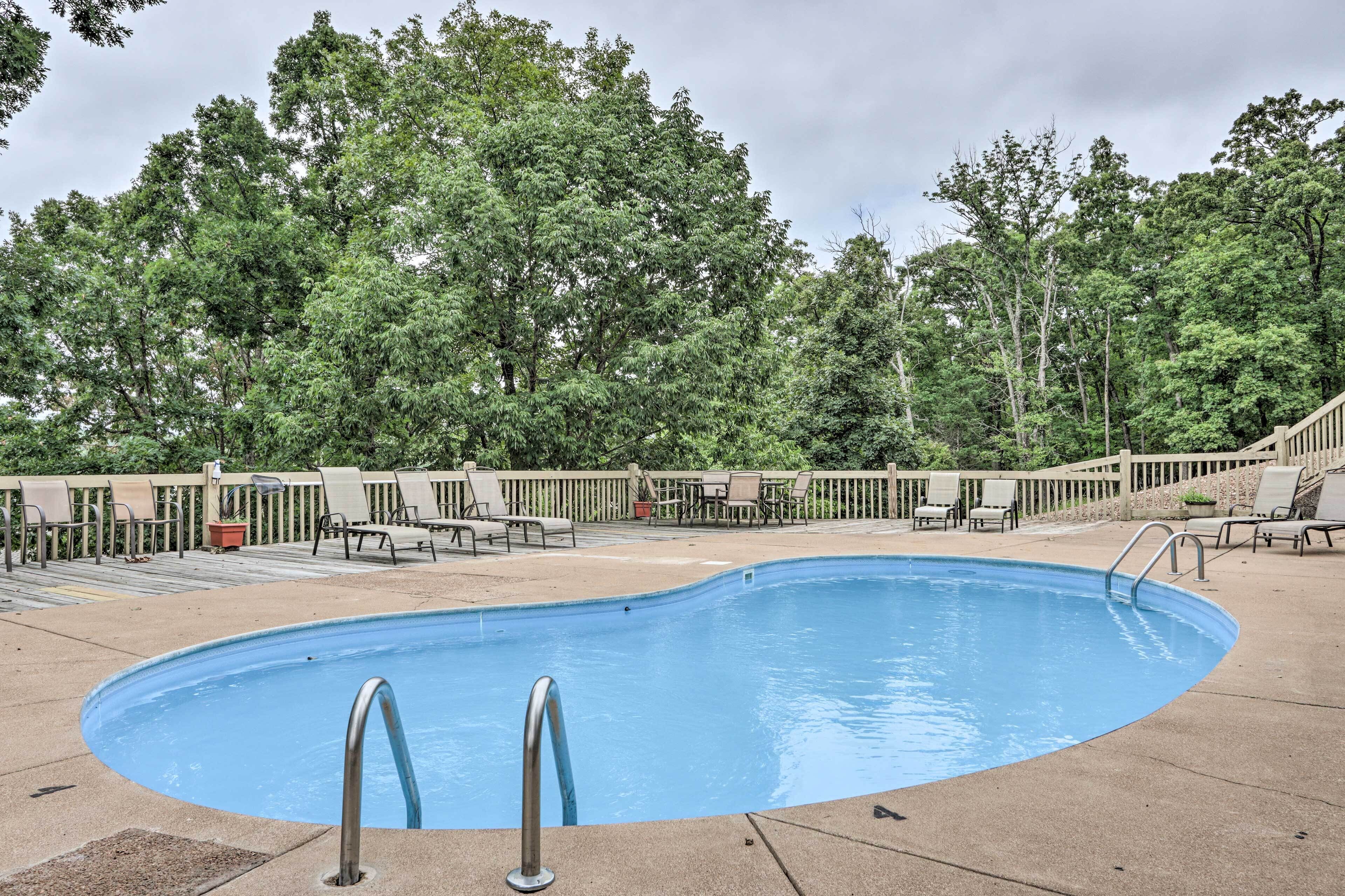 A swimming pool with two ladders, surrounded by lounge chairs and a wooden deck.