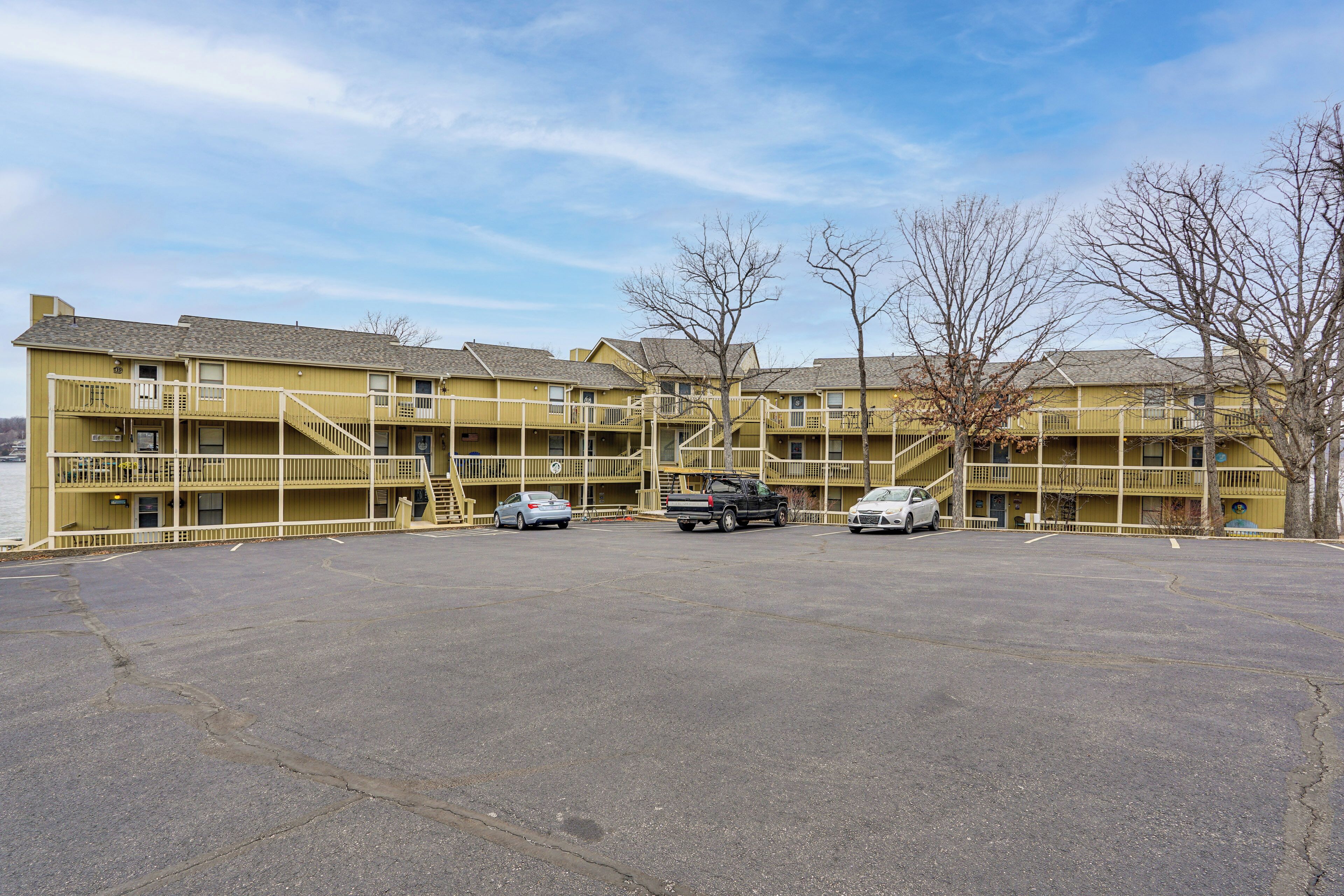 A multi-story motel with a parking lot, staircases to upper floors, and a clear sky.