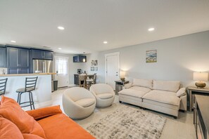 A modern living room with a sofa, two armchairs, a coffee table, and a rug. There is a kitchen area with a refrigerator, cabinets, and a dining table with chairs. - Sand Dunes Escape: Epic Stargazing! (Blanca)
