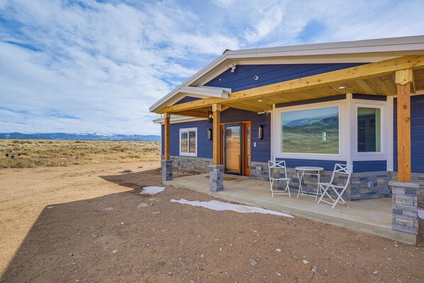 A modern house with a covered porch, stone pillars, and large windows. - Sand Dunes Escape: Epic Stargazing! (Blanca)