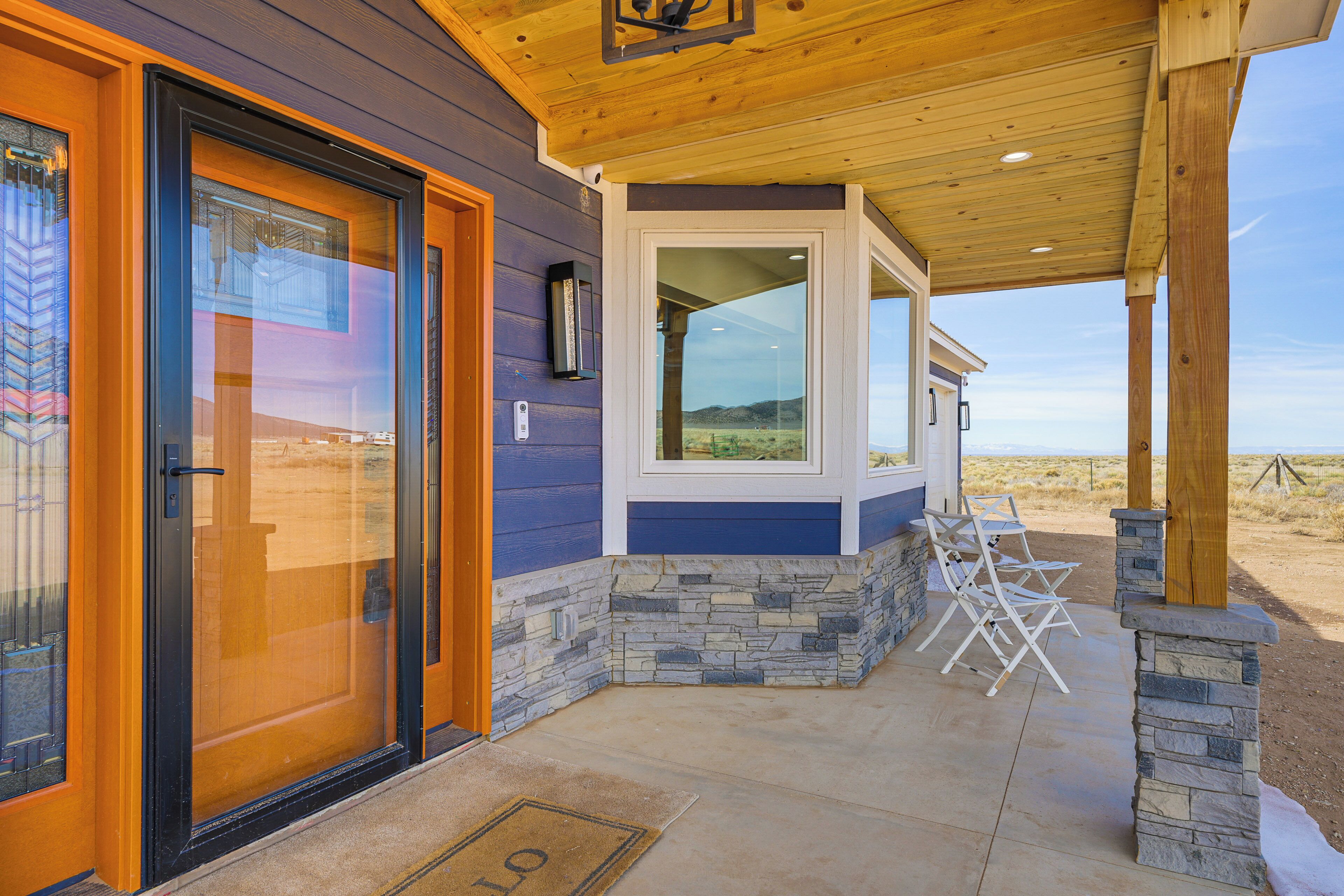 A covered outdoor area with a stone and wood exterior, a glass door, and a bench.