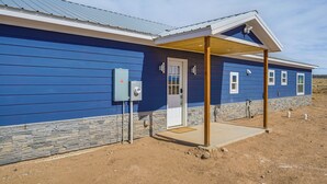 A single-story building with a blue exterior, a stone foundation, and a covered porch.