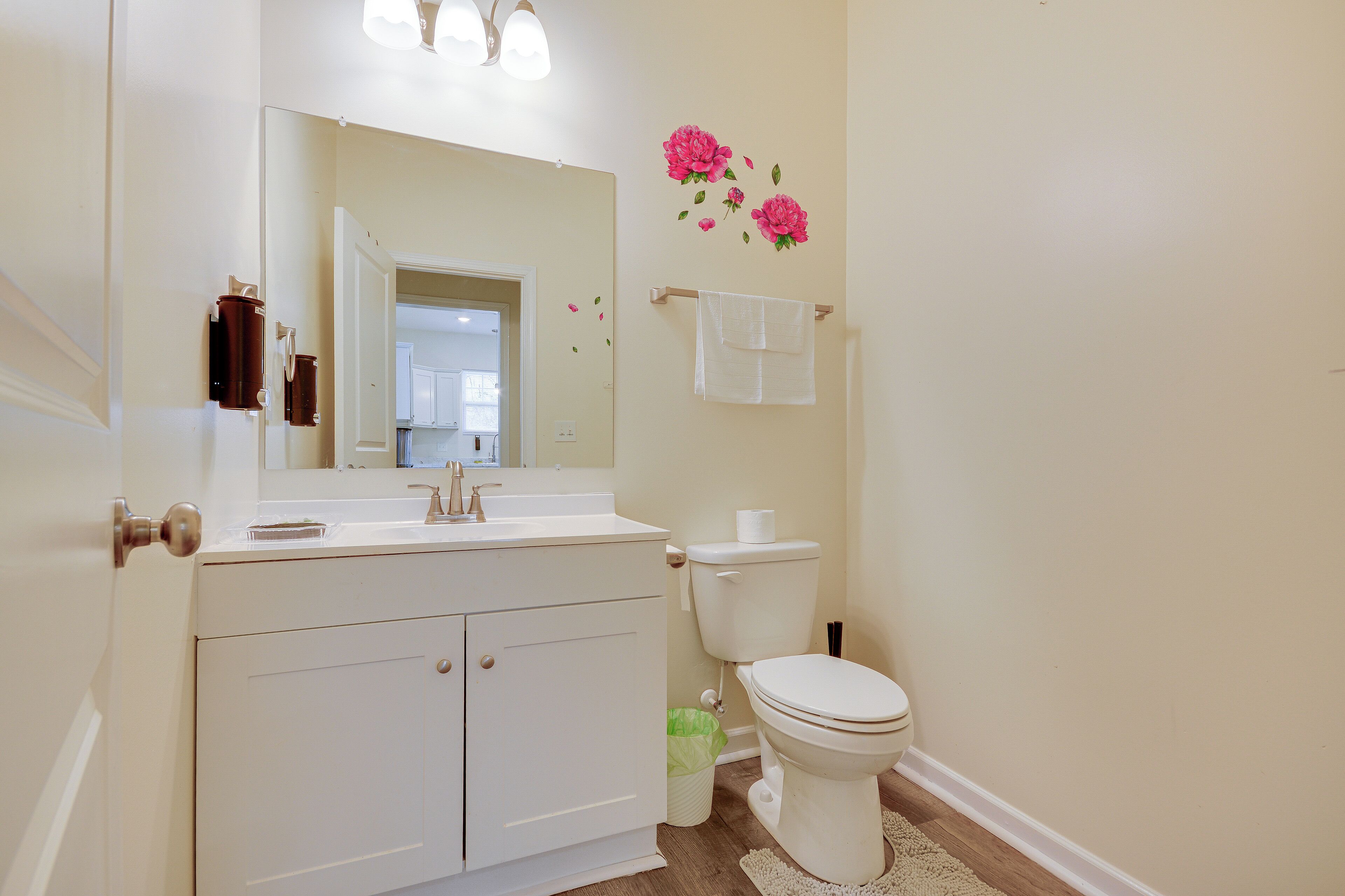 A bathroom with a white vanity, a toilet, a mirror, and a wall-mounted towel rack.