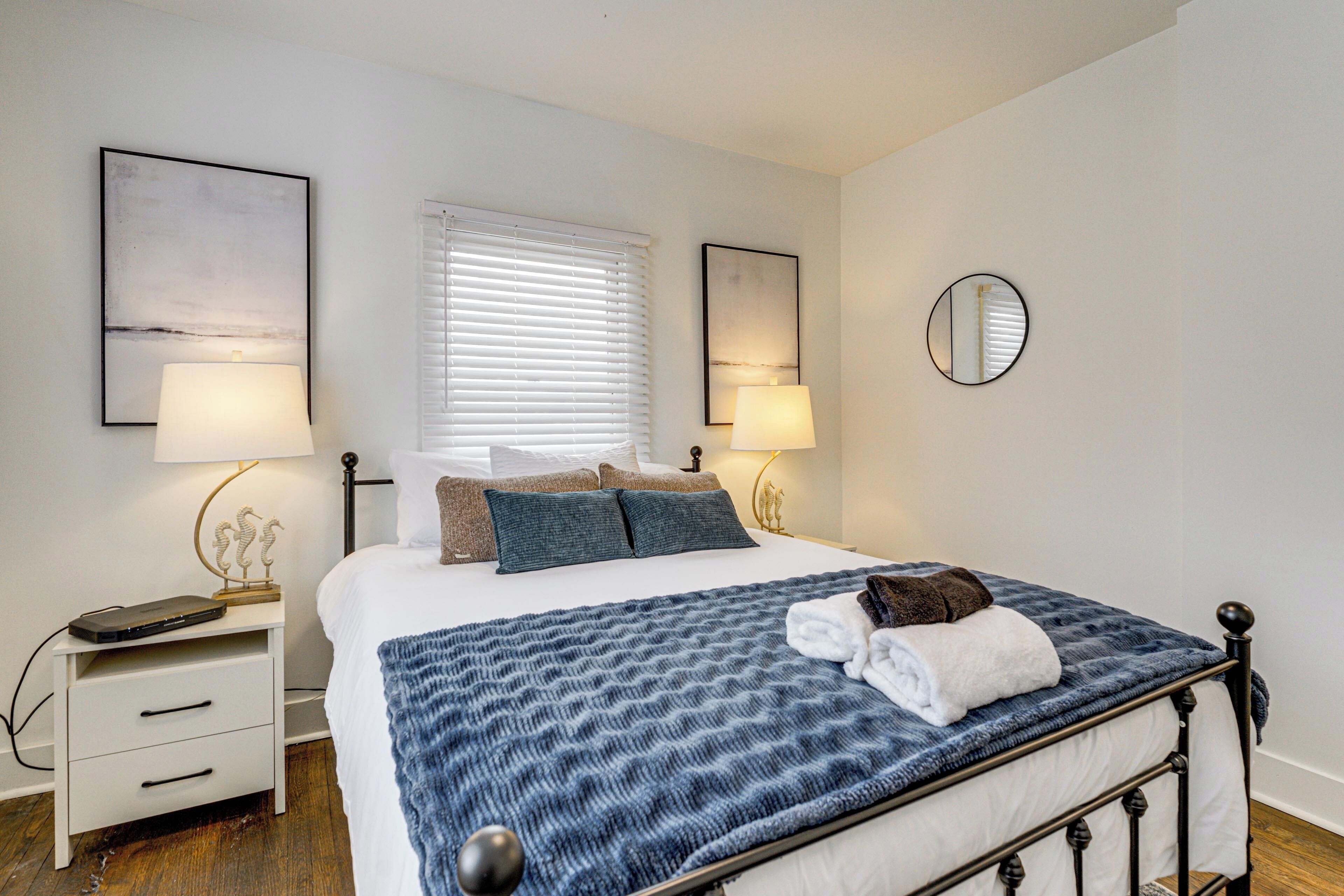 A neatly arranged bedroom with a bed, bedside tables, lamps, and a mirror.