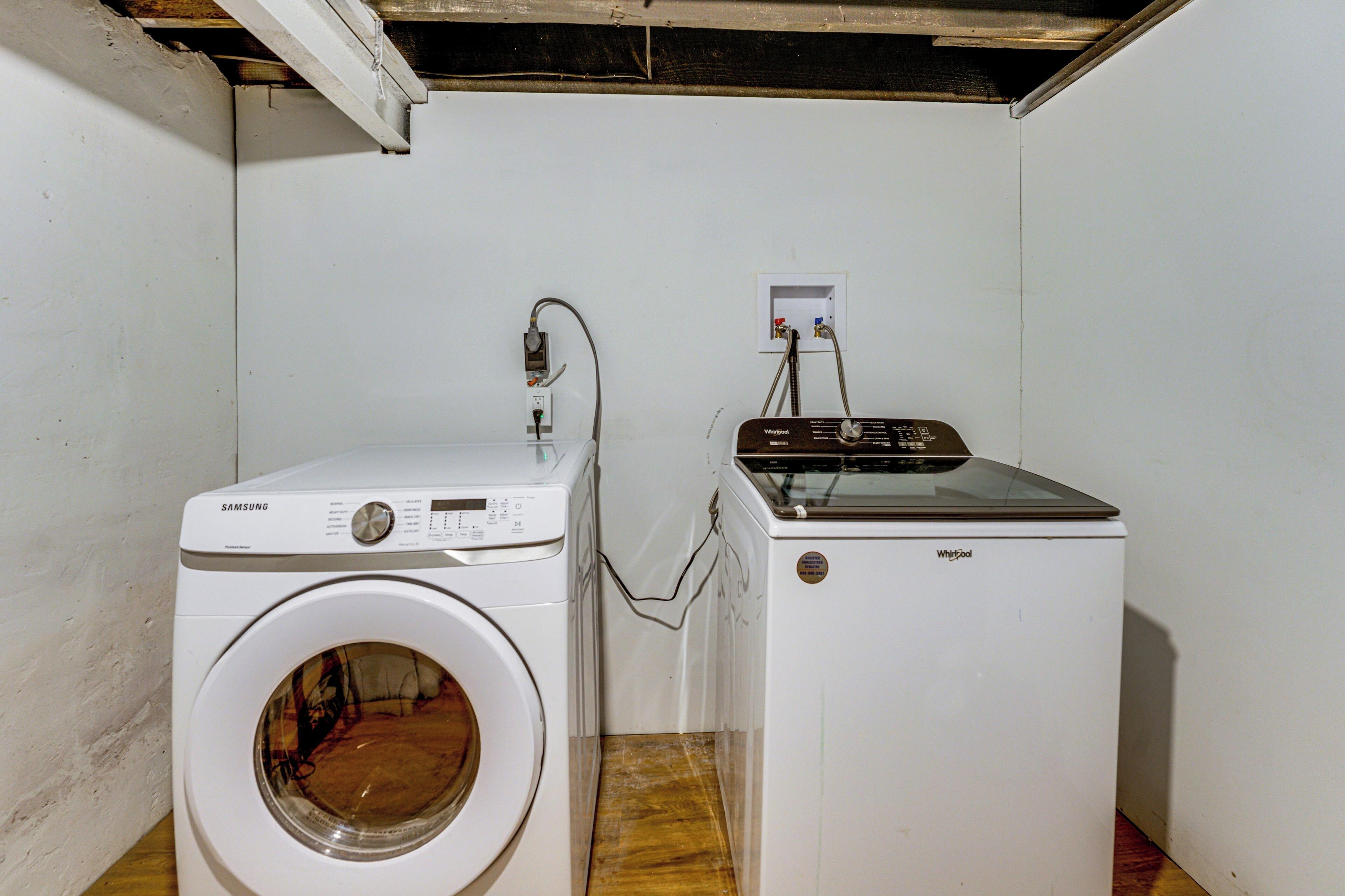A laundry room with a Samsung washer and a Whirlpool dryer, both white, with visible control panels and hoses.