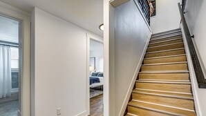 A staircase with wooden steps and a handrail, leading to a bedroom with a bed and a nightstand. - Spacious & Updated Group Getaway in Detroit! (Detroit)