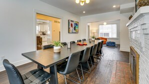 A modern dining area with a long table, black chairs, and a potted plant. - Spacious & Updated Group Getaway in Detroit! (Detroit)