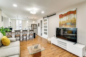 Een moderne woonkamer met een televisie, bank en eethoek.