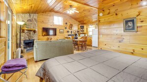 Ein gemütliches Blockhaus mit Holzinnenraum, Kamin, Essbereich und einem bequemen Bett.