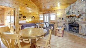 Ein rustikales Blockhaus-Interieur mit Kamin aus Stein, Holzmöbeln und einer gemütlichen Sitzecke.