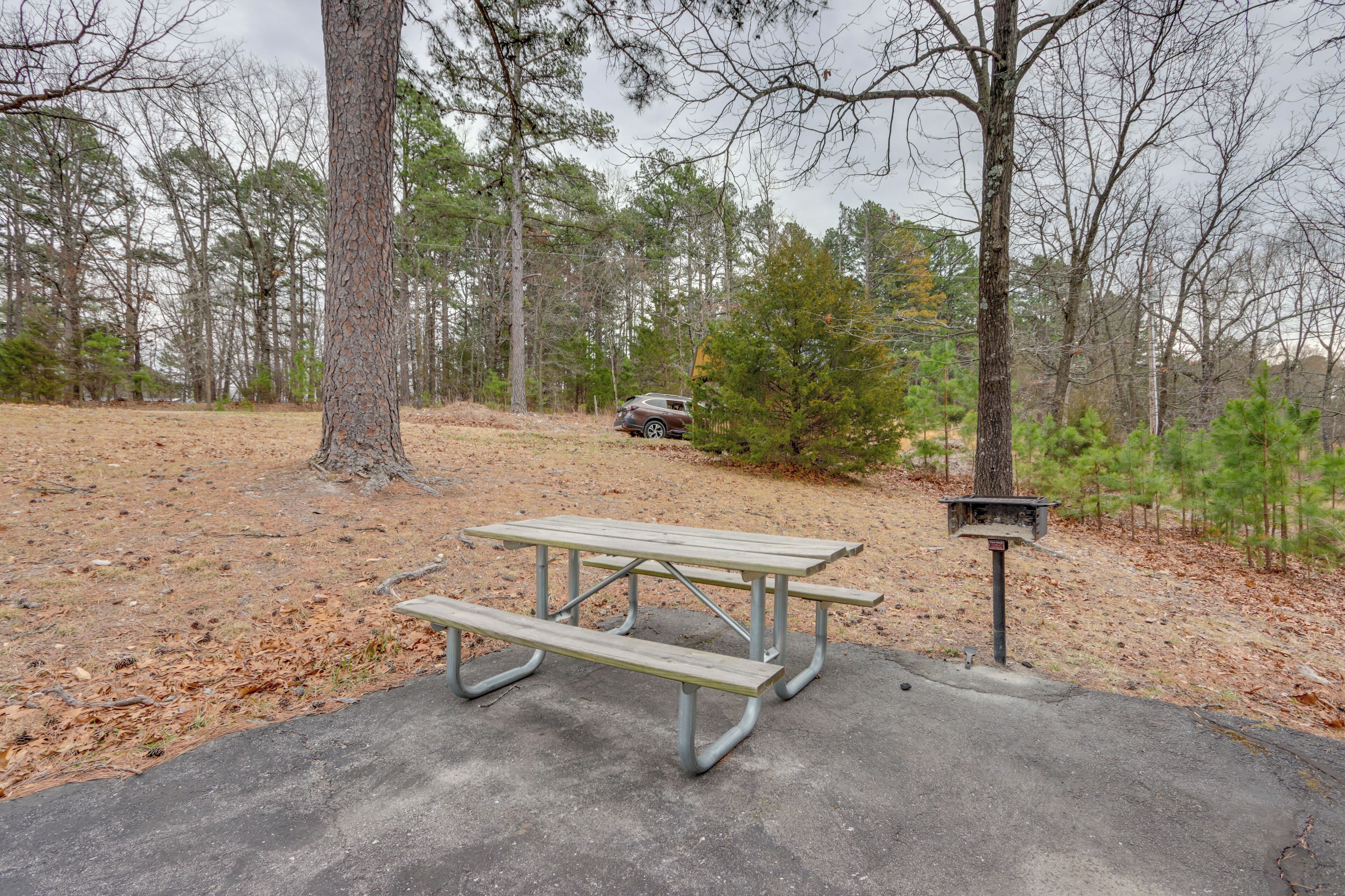 A picnic table with benches in a wooded area.