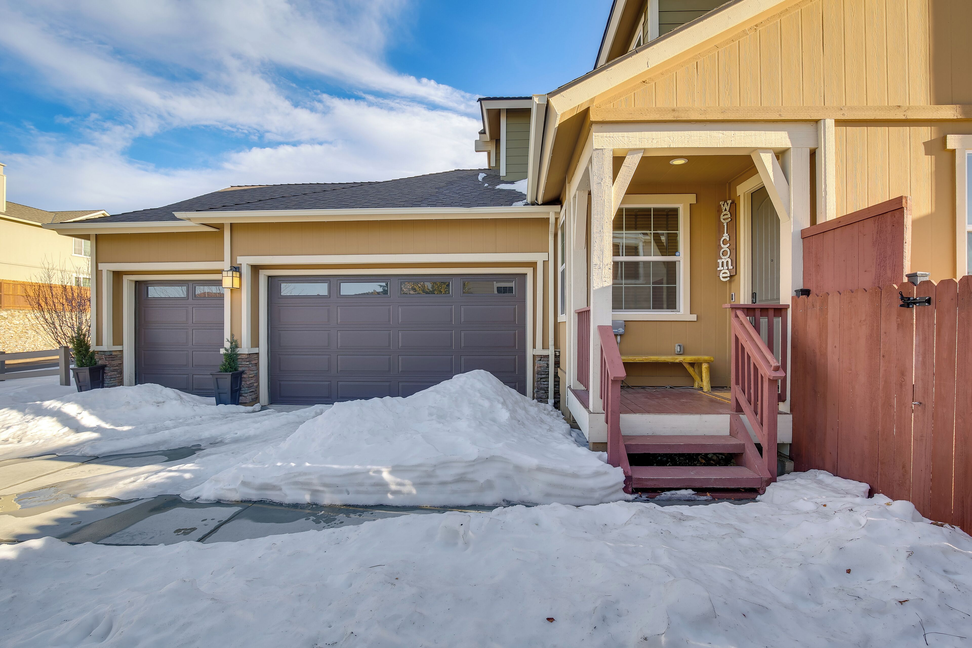 A residential house with a garage, a front porch, and a wooden fence.