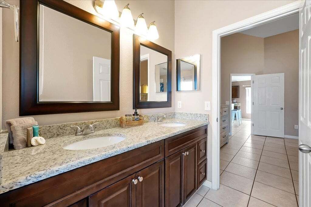 Un baño con dos lavamanos, un espejo grande y un mueble de tocador con cajones.