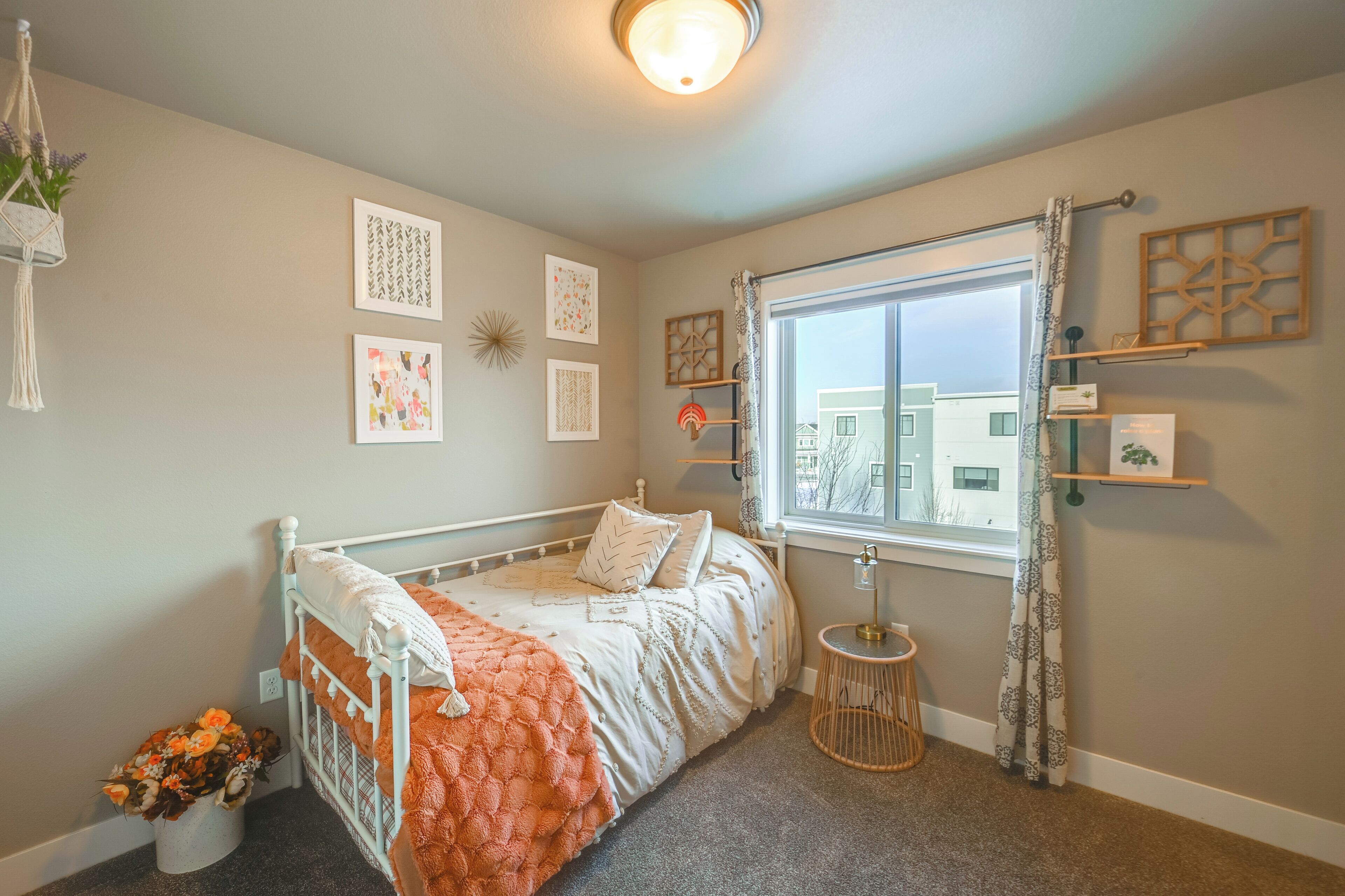 Un dormitorio con cama, ventana y adornos en la pared.