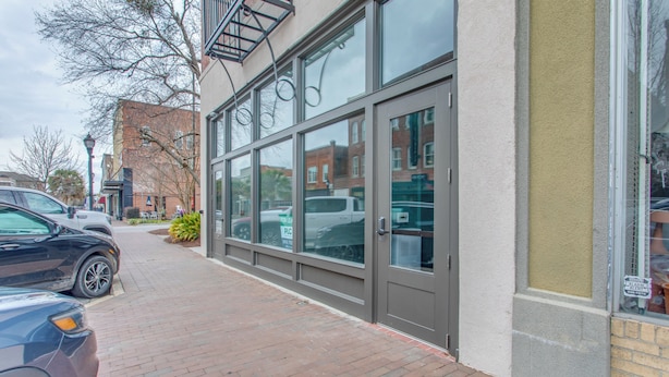 A building with large windows and a brick sidewalk.