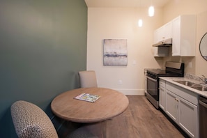 A compact kitchen with a round dining table, a single chair, and a small cabinet above the stove. - Walkable Couples Retreat in Downtown Florence (Florence)