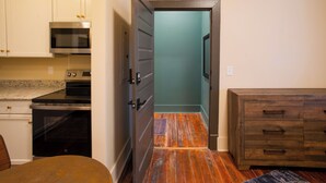 A kitchen with white cabinets, a microwave, an oven, and a wooden cabinet. - I-95 & I-20 Stopover: Walkable Florence Condo (Florence)
