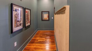 A hallway with wooden flooring, framed artwork on the walls, and a mirror. - I-95 & I-20 Stopover: Walkable Florence Condo (Florence)
