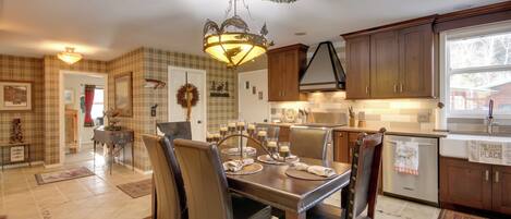 A dining area with a chandelier, wooden cabinets, and a view of the kitchen.