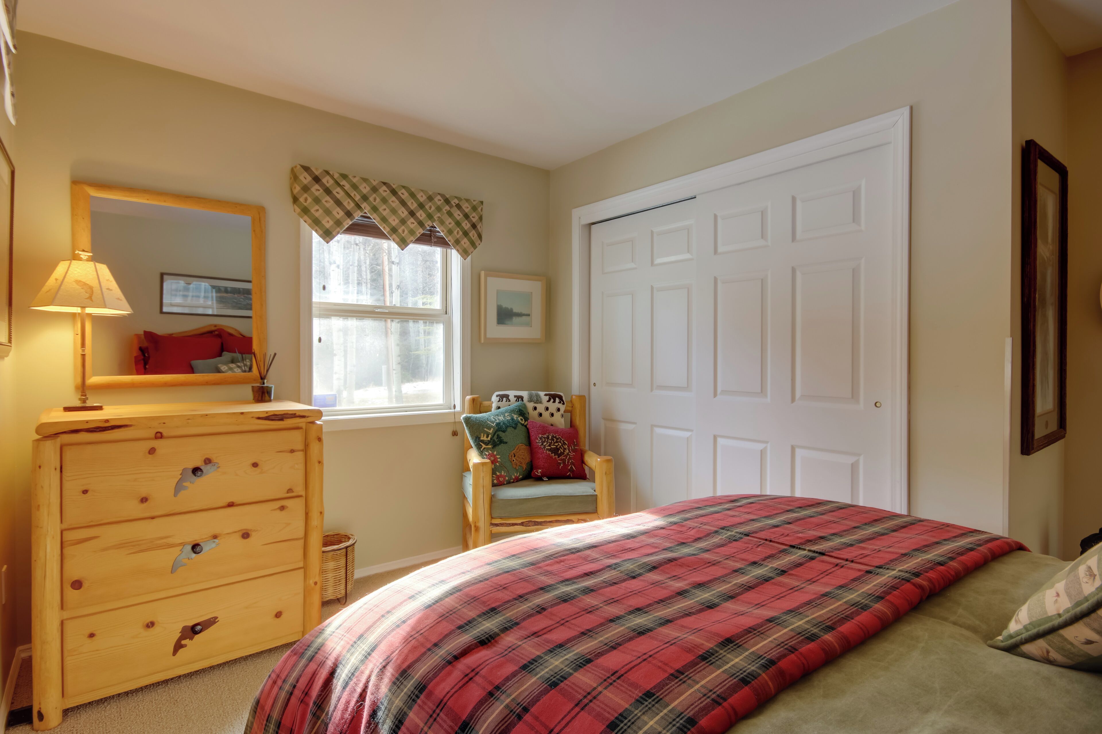 A bedroom with a bed, dresser, chair, window, and door.