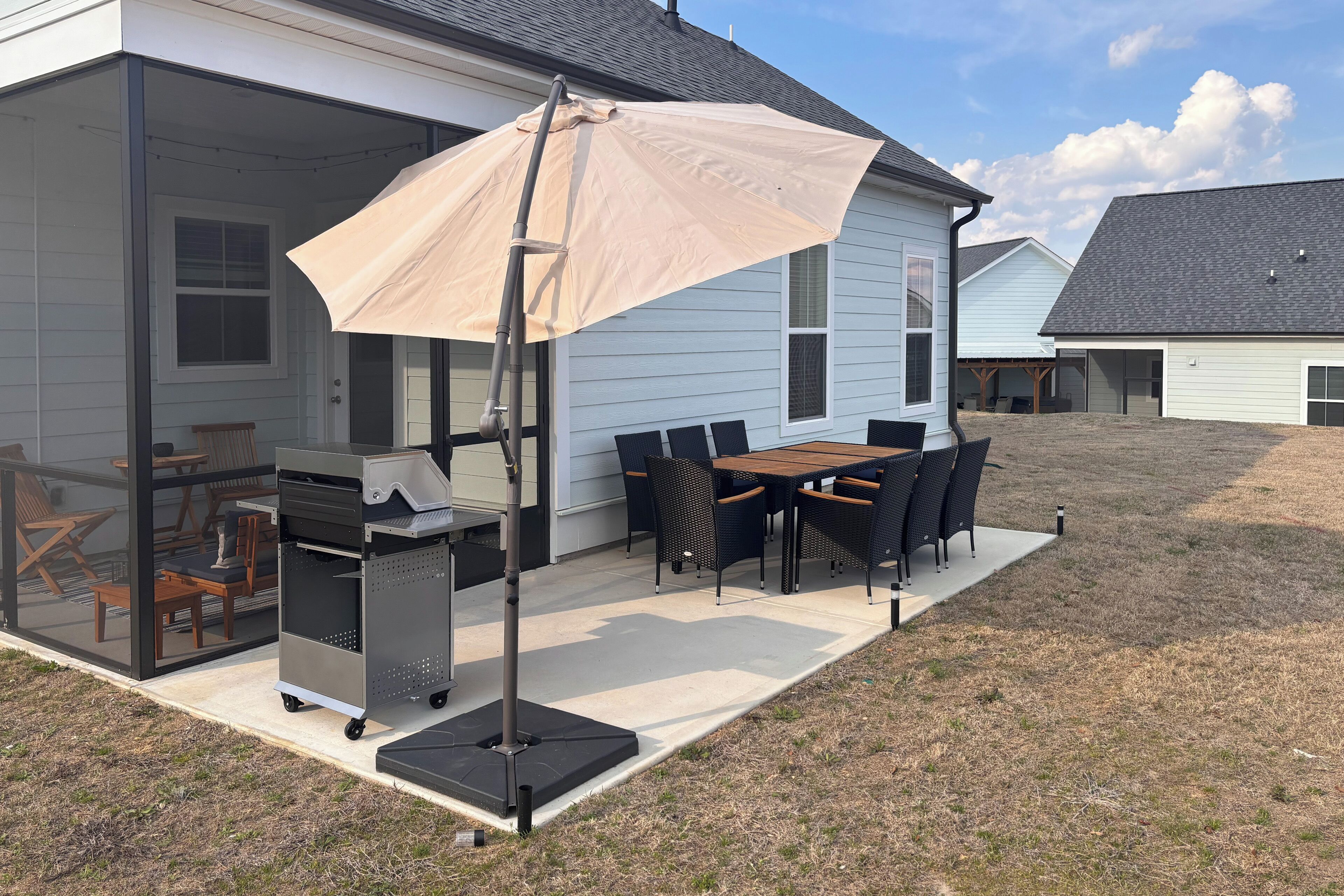 A covered patio with a grill, dining table, and chairs.