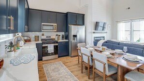 A modern kitchen with dark cabinets, a microwave, a refrigerator, and a dining area with a table set for four. - The Hideaway at Lake Greenwood Marina Access (Greenwood)