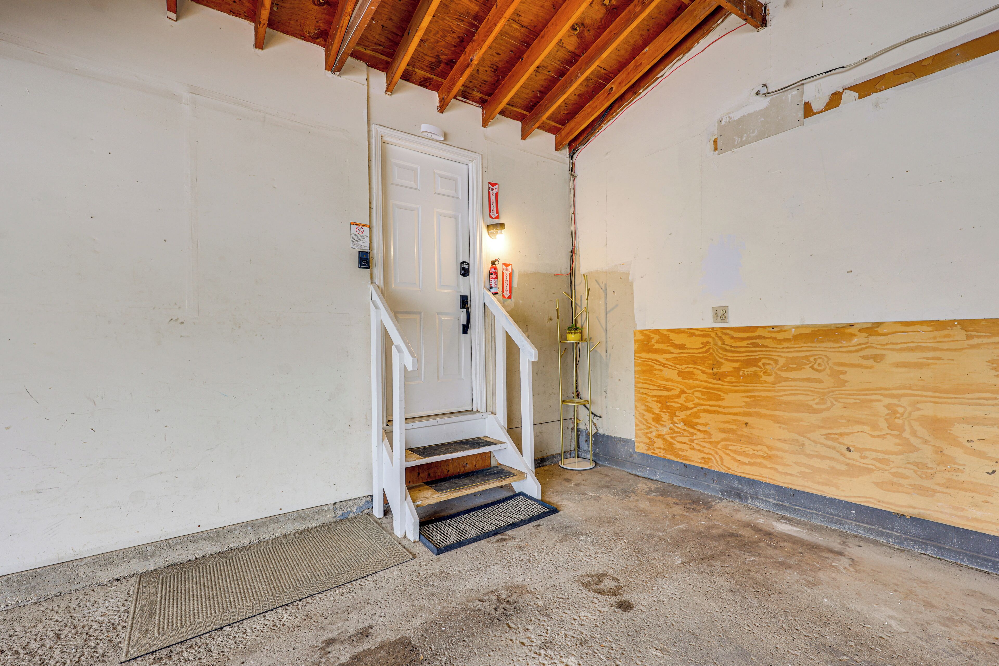 A staircase leading to a door, a wooden wall, and a concrete floor.
