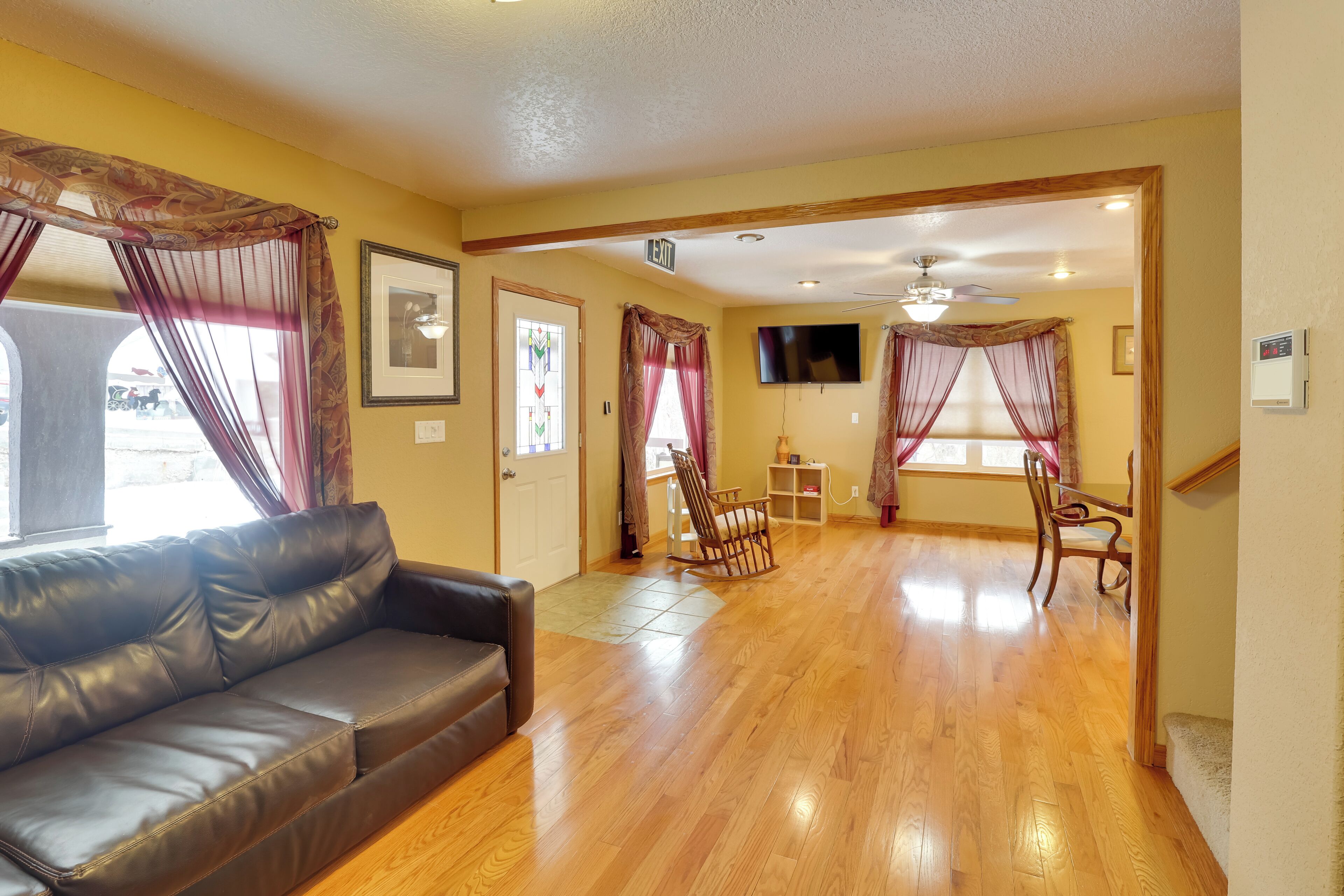 A living room with a leather sofa, wooden flooring, and a TV mounted on the wall.